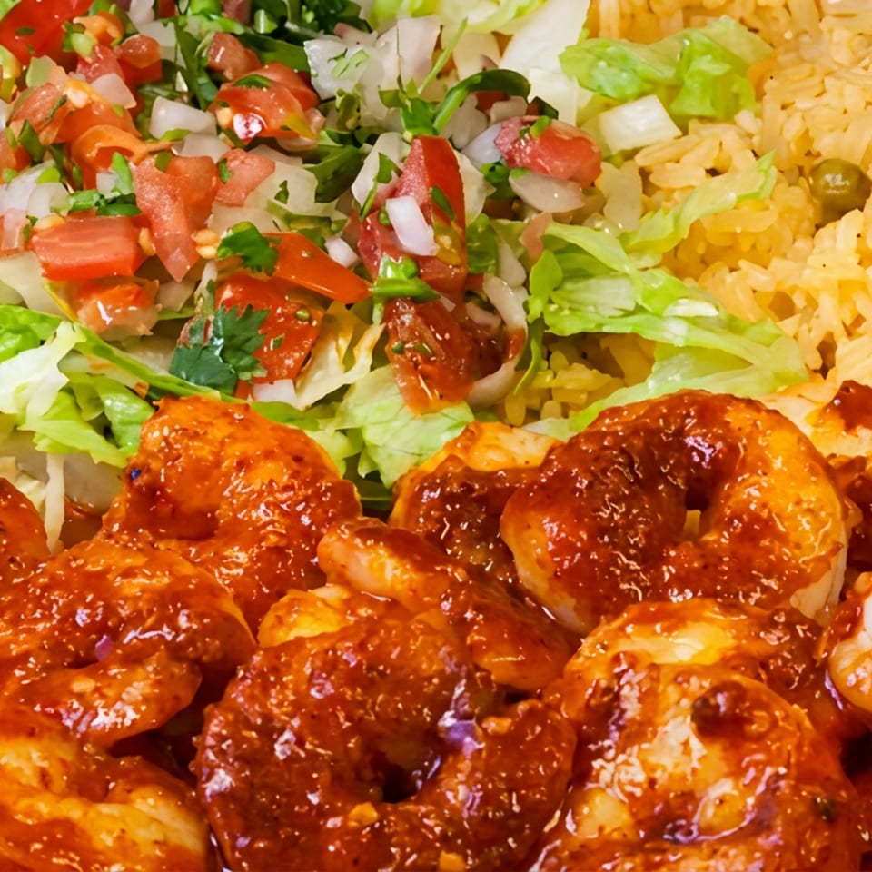 Spicy shrimp with Mexican rice and a fresh pico de gallo salad on a plate.