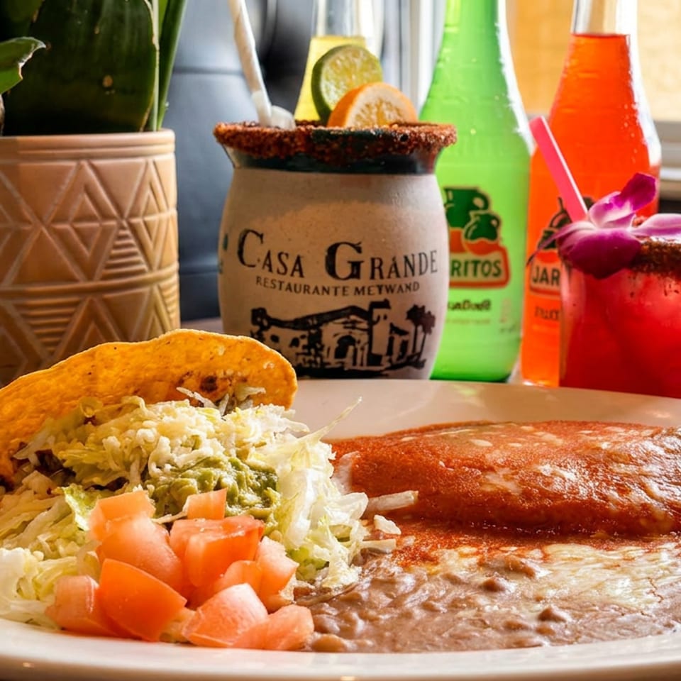 Casa Grande Mexican combo plate with taco, enchilada, beans, and colorful drinks.