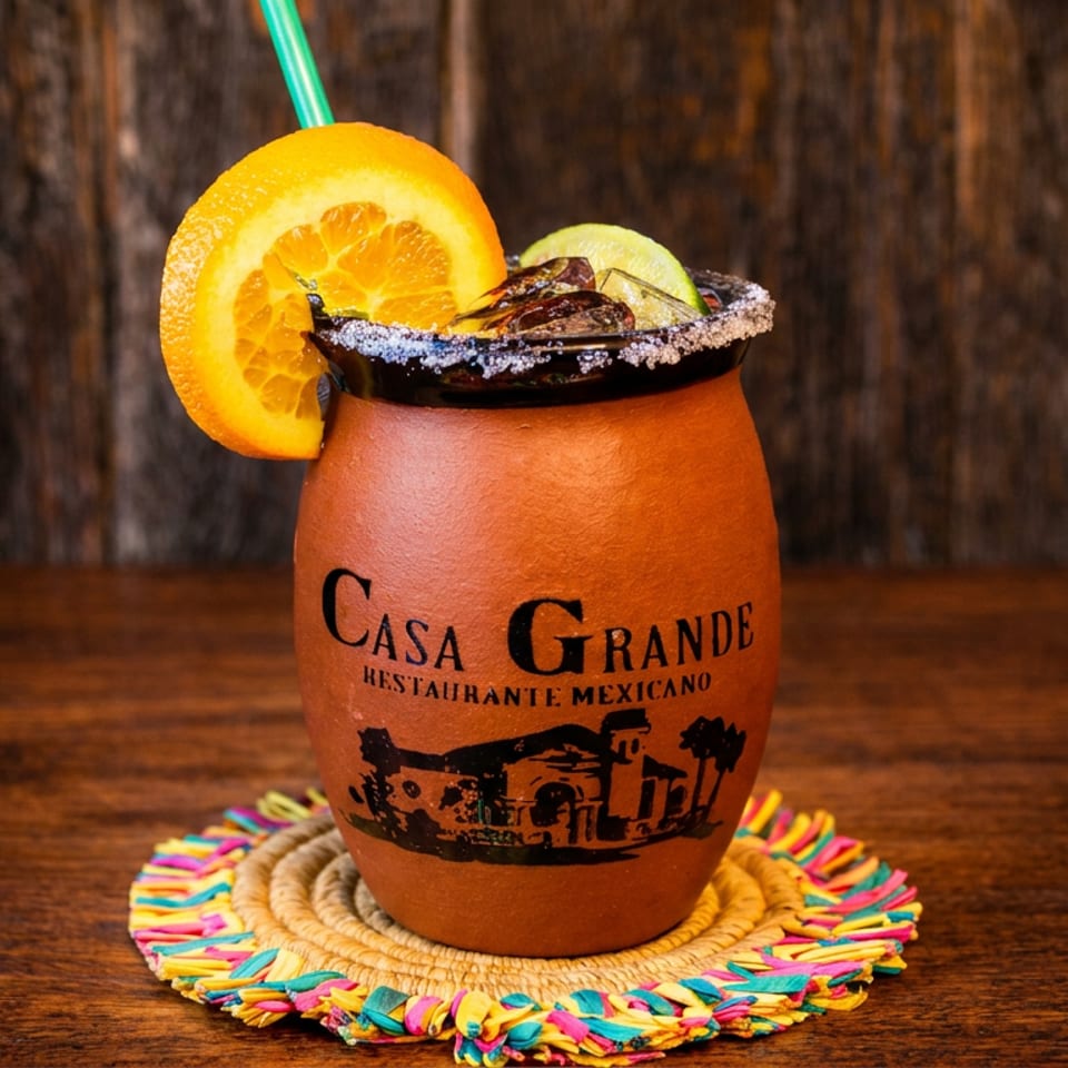 Clay mug drink from Casa Grande with orange, lime, and salted rim on a colorful coaster.
